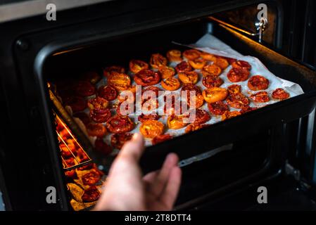 Schalen mit frischen Kirschtomaten auf Gestellen trocknen im Ofen Stockfoto