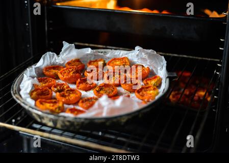 Schalen mit frischen Kirschtomaten auf Gestellen trocknen im Ofen Stockfoto