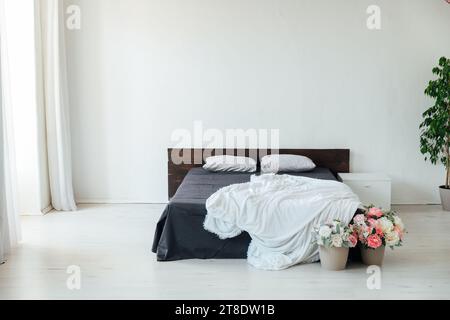 Ein dunkles Bett mit weißer Decke steht auf weißem Hintergrund Stockfoto