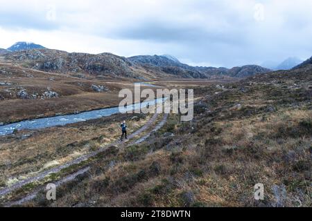 Frau läuft auf unbefestigtem Weg in den Bergen Stockfoto