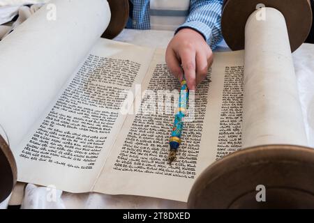 Nahaufnahme einer Hand, die einen yad oder Zeiger hält, um den Leser durch den hebräischen Text der jüdischen Thora zu führen. Stockfoto