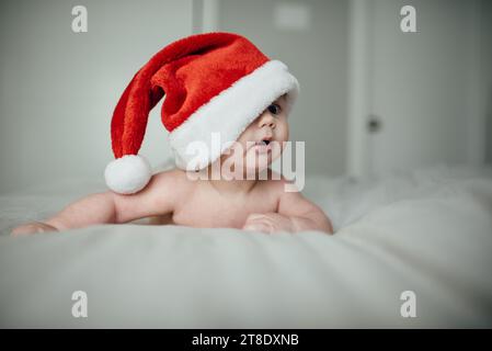 Nahaufnahme eines kleinen Jungen mit Weihnachtsmannmütze, der umfällt Stockfoto