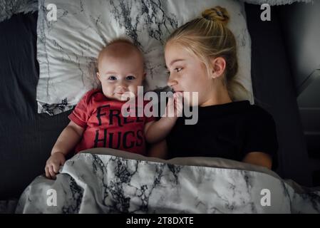 Draufsicht des Babys, das im Bett liegt und die Kamera während des Kuschelns betrachtet Stockfoto