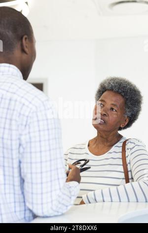 afroamerikanischer Arzt, der mit einer älteren Frau im Krankenhausempfang spricht Stockfoto