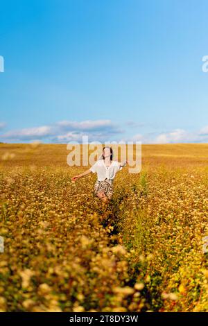 Junge Frau in einem gelben Sommerfeld bei Sonnenuntergang. Stockfoto