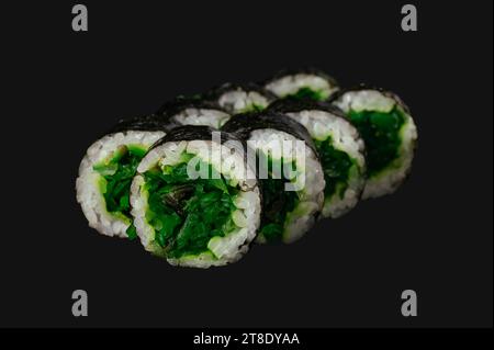 Sushi-Brötchen mit Chuka-Salat auf schwarzem Hintergrund. Stockfoto