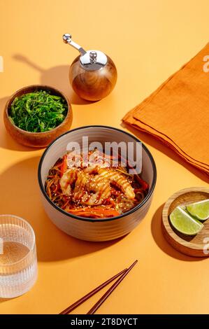 asiatische Nudeln mit Huhn und Gemüse. Menü. Orangefarbener Hintergrund Stockfoto