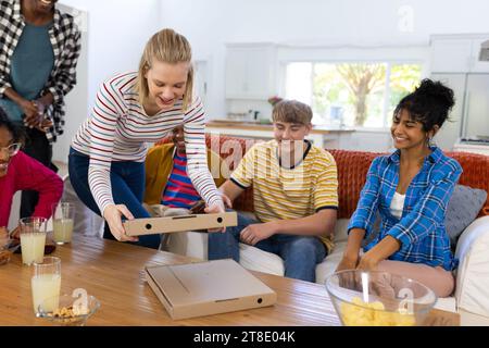 Glückliche Gruppe von Teenagerfreunden, die auf der Couch sitzen und Pizza essen Stockfoto