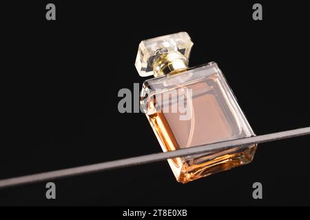 Schönheitsprodukt Parfümflasche auf Glasregal, Kopierraum auf schwarzem Hintergrund Stockfoto