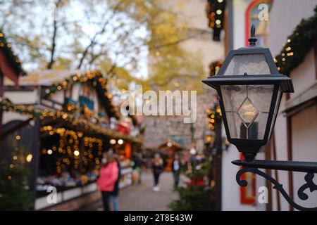 Konzentrieren Sie sich auf die Straßenlaterne. Europäische Stadt während der Weihnachtszeit erwacht das festliche Ambiente des Weihnachtsmarktes zum Leben. Malerische und magische urbane Umgebung Stockfoto