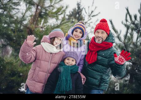 Foto einer freundlichen, aufgeregten kleinen Frau, die Mäntel, die Arme winkend, zusammen lächelnd im urbanen Waldpark Stockfoto