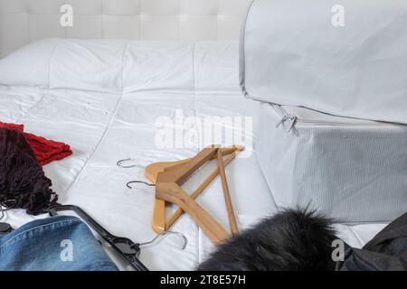 Horizontales Foto, Winterkleidung, Kleiderbügel und Stoffkästen auf einem Bett, die bis Anfang des Frühlings gesammelt werden. Wandwechsel. Stockfoto