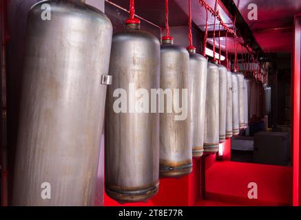 Schmutzige Arbeit. Produktionswerkstatt für industrielle Feuerlöscher Tubenlackierwerkstatt. Nicht standardmäßige Arbeitsbedingungen. Stockfoto