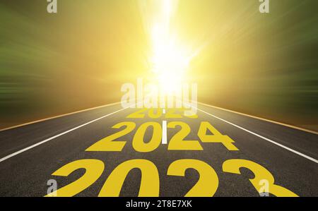 Das Wort 2024 bis 2028 steht auf der Autobahn mitten auf einer leeren Asphaltstraße bei goldenem Sonnenaufgang. Neujahrskonzept 2024. Stockfoto