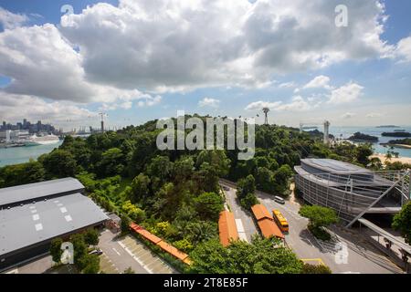 Aus der Vogelperspektive von Sentosa, teilweise bedeckt von grüner Vegetation, Strand und in Betrieb befindlichen Seilbahnen, Singapur. Stockfoto