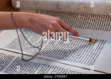 Nahaufnahme einer Hand, die einen yad oder Zeiger hält, um den Leser durch den hebräischen Text der jüdischen Thora zu führen. Stockfoto