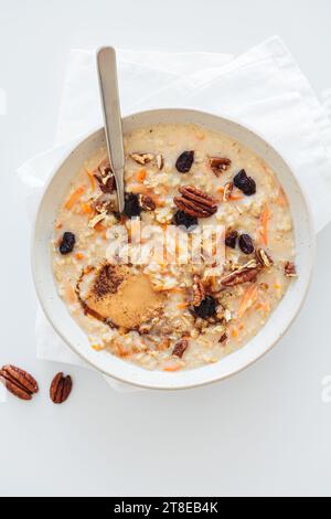 Karottenkuchen Haferflocken mit getrockneten Preiselbeeren, Pekannüssen und Erdnussbutter in weißer Platte, weißer Hintergrund, Draufsicht. Nahrhaftes gesundes Winterfrühstück c Stockfoto