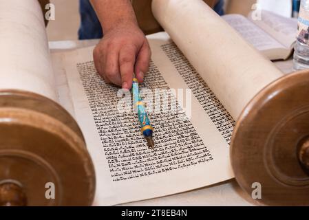 Nahaufnahme einer Hand, die einen yad oder Zeiger hält, um den Leser durch den hebräischen Text der jüdischen Thora zu führen. Stockfoto