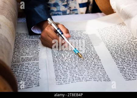 Nahaufnahme einer Hand, die einen yad oder Zeiger hält, um den Leser durch den hebräischen Text der jüdischen Thora zu führen. Stockfoto