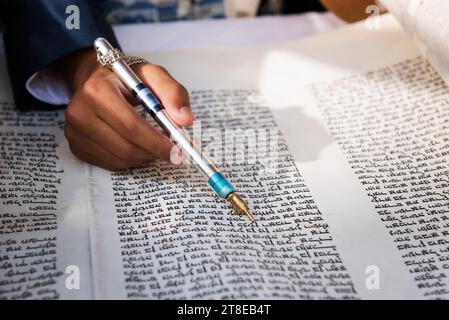 Nahaufnahme einer Hand, die einen yad oder Zeiger hält, um den Leser durch den hebräischen Text der jüdischen Thora zu führen. Stockfoto