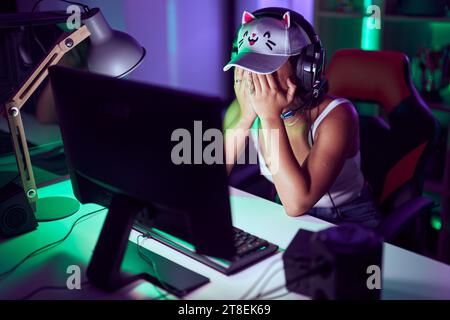 Junge schöne hispanische Frau Streamer betonte mit Computer im Spielzimmer Stockfoto