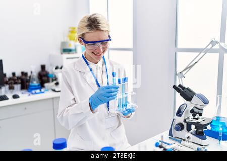 Junge blonde Wissenschaftlerin, die Reagenzgläser im Labor analysiert Stockfoto