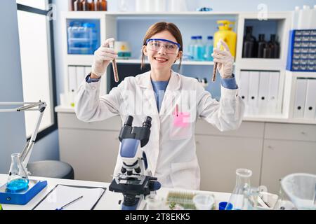 Junge blonde Wissenschaftlerin, die Reagenzgläser im Labor analysiert Stockfoto