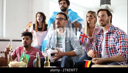 Fröhliche und glückliche Gruppe von Freunden, die Olympische Spiele im fernsehen anschauen. Stockfoto