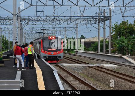 Passanten, die auf einen elektrischen Zug warten, der am ländlichen Bahnhof in der Nähe von Surakarta, Indonesien, hält. Stockfoto