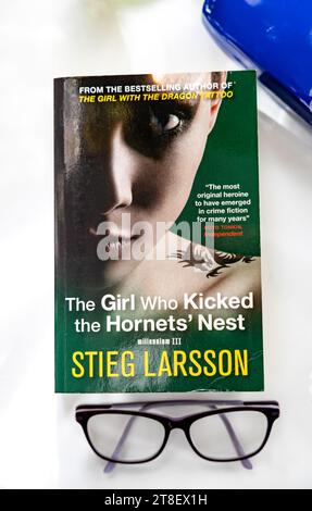 Vertikales Porträt-Konzeptbild mit dem Buch The Girl Who Kicked the Hornissen' Nest von Stieg Larsson mit Lesebrille und Brillenetui im Blick Stockfoto