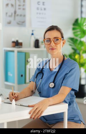 Porträt einer schönen Ärztin, die am Schreibtisch in einer Arztpraxis sitzt. Stockfoto