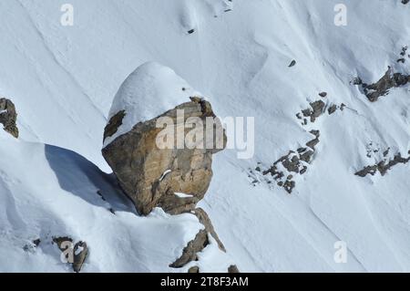 Ausbalancierter, ausbalancierter Felsen auf einem schneebedeckten Berghang im Winter Stockfoto