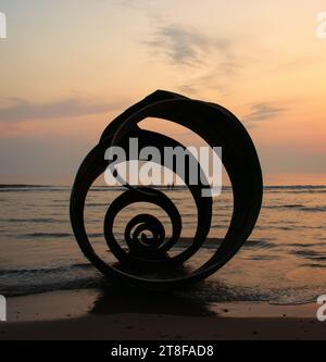 Zwei ferne Figuren, die im Meer herumtoben, sehen Sie durch Mary's Golden Shell am Livereys Beach, Fylde Coast, Großbritannien Stockfoto