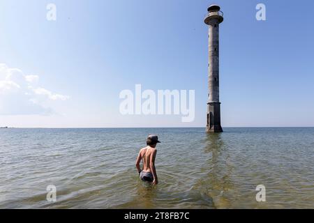 Kid Tourist spazieren im Meer zum malerischen Kiipsaare Leuchtturm an der Spitze der Harilaid Halbinsel auf der Insel Saaremaa, Estland Stockfoto