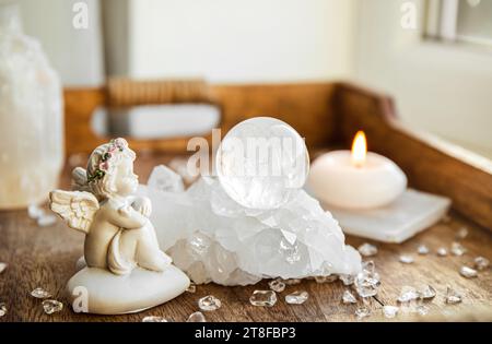 Spirituelles Engel-Botschaftskonzept. Kleine süße Engelsfigur sitzt drinnen neben Kristall-Edelsteinkugel. Stockfoto