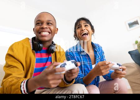 Glückliche Teenager-Freunde, die auf der Couch sitzen und zu Hause Videospiele spielen Stockfoto