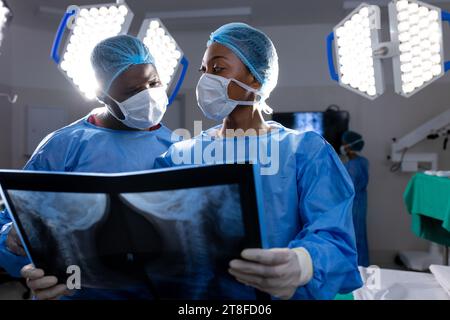 afroamerikanische Ärztinnen und Ärzte mit Gesichtsmasken, die im Krankenhaus Röntgenstrahlen betrachten Stockfoto