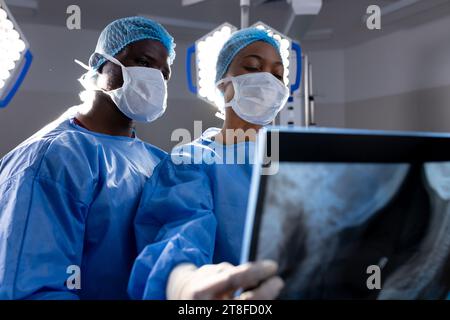 afroamerikanische Ärztinnen und Ärzte mit Gesichtsmasken, die im Krankenhaus Röntgenstrahlen betrachten Stockfoto