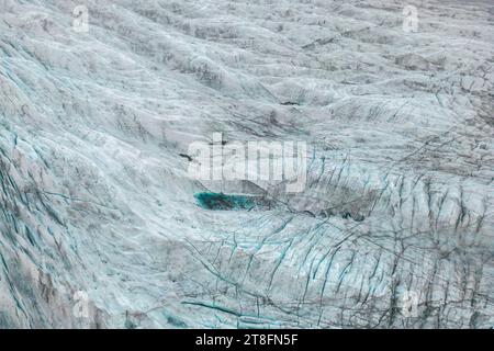 Nahaufnahme der Gletscheroberfläche mit komplizierten Mustern und einer tiefblauen Spalte Stockfoto