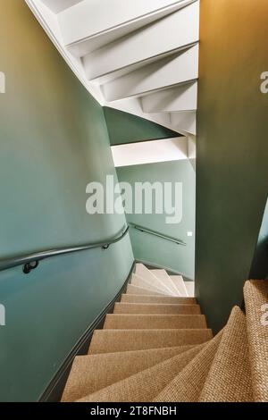 Blick auf eine schmale Treppe mit Teppichboden und grüne Wand nach unten in ein modernes Haus Stockfoto