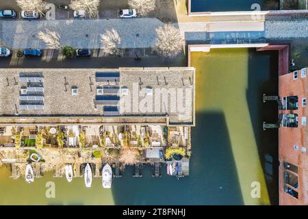 Blick aus der Vogelperspektive auf Boote, die am Hafen vertäut sind, und Solarpaneele auf dem Dach des Gebäudes in der Stadt während des sonnigen Tages Stockfoto