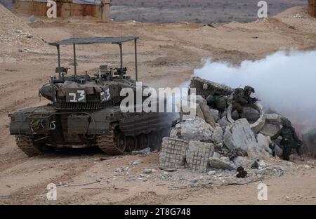 Israelische Infanterie-Soldaten der 55. Brigade von Fallschirmjägern mit leichten Waffen, während sie am 20. November 2023 in einer Feuerübung vor der Basis Tze'elim in Südisrael nahe der Grenze zum Gazastreifen trainieren, zusammen mit Merkava-Panzern des Panzerkorps, der einen weißen Rauch ausspuckt, um den Bodentruppen Deckung zu bieten. Die Soldaten sind alle Reservetruppen der IDF und waren noch nicht im Gazastreifen. Einige der Soldaten kehrten nach dem Terroranschlag der Hamas auf südliche israelische Gemeinden am 7. Oktober 2023 sofort aus dem Ausland nach Israel zurück. Foto von Jim Hollander/UPI Stockfoto