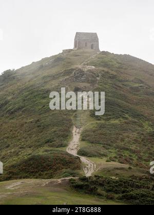 Meeresnebel weht über die auf einem Hügel gelegene Kapelle von Rame Head an der kornischen Küste. Stockfoto