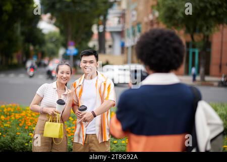 Fröhliches Paar bittet einen Freund, sein Foto auf der Straße zu machen Stockfoto