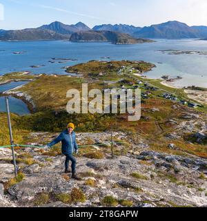 Blaubekleidete Frau Wanderung vom Nordkollen nach Sommarøy und Kvaløya, wunderbarer Panoramablick auf Insel, Dorf und Hafen Stockfoto