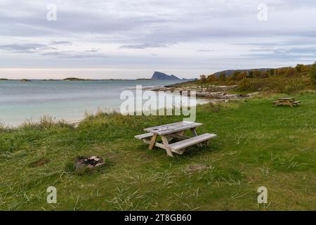 Grillplatz am Atlantikufer in der Nähe von Sommarøy, Norwegen. Sandstrand mit Grill, Parkbank und Entspannungsbereich, am türkisfarbenen Meer wie Karibik Stockfoto