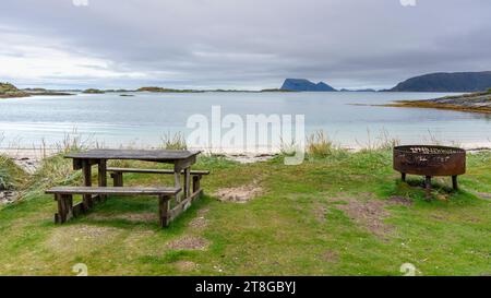 Grillplatz am Atlantikufer in der Nähe von Sommarøy, Norwegen. Sandstrand mit Grill, Parkbank und Entspannungsbereich, am türkisfarbenen Meer wie Karibik Stockfoto