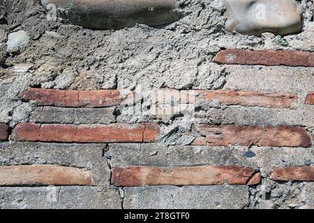 Steinziegel Wandmuster Textur Hintergrund Oberfläche Beton. Zerquetschte Steine und Ziegel. Alte Kratzer und Flecken, Makrofoto. Hochwertige Fotos Stockfoto