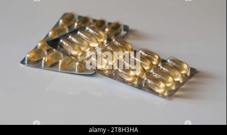 Zwei Blisterpackungen mit gelb-orangefarbenen Medikamententabletten, Omega-Tabletten auf dem Tisch. Arzneimittel, Medikamente, Gesundheitswesen, Behandlungskonzept Stockfoto