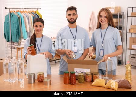 Porträt von Freiwilligen, die Lebensmittel am Tisch im Lager verpacken Stockfoto